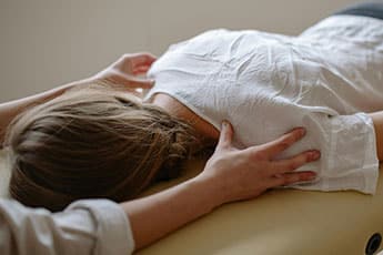 Therapist's hands on a person's back during a massage on a massage table